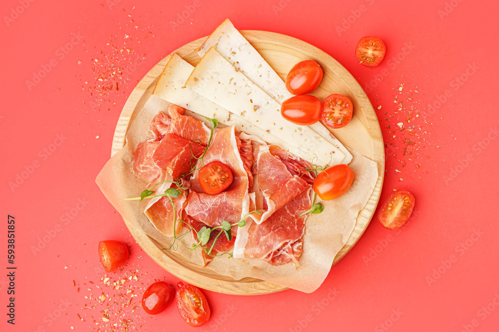 Plate with slices of tasty jamon and cheese on red background