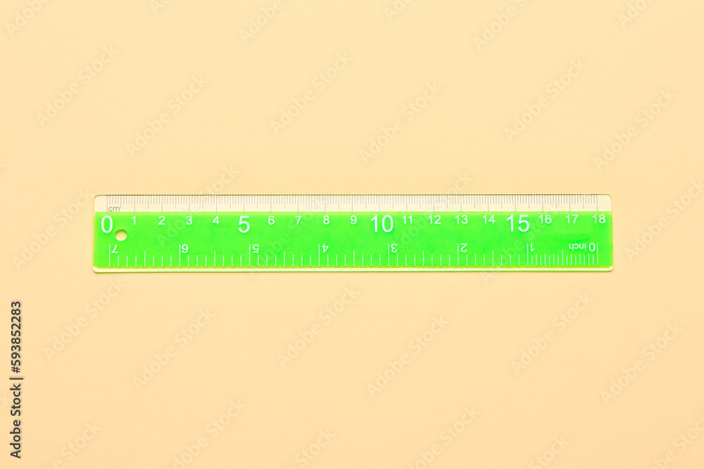 Green plastic ruler on beige background