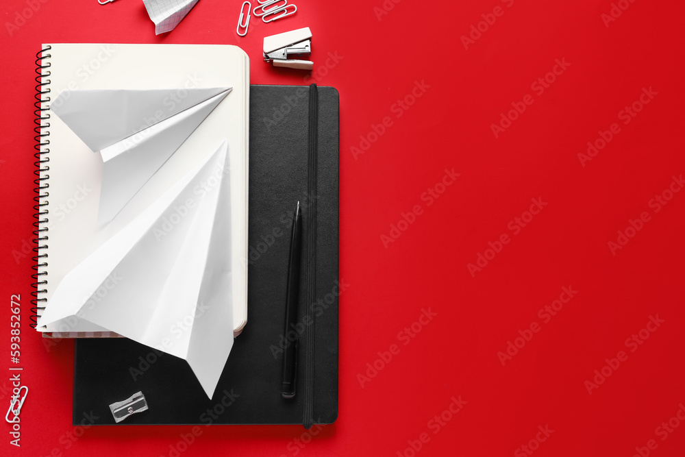 Composition with stationery supplies and paper planes on red background