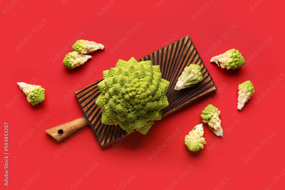 Composition with romanesco cabbage and wooden board on red background