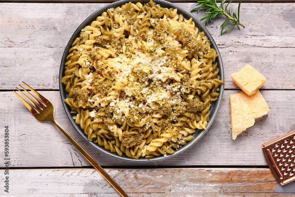 Plate of tasty Italian pasta with Parmesan cheese on light wooden background