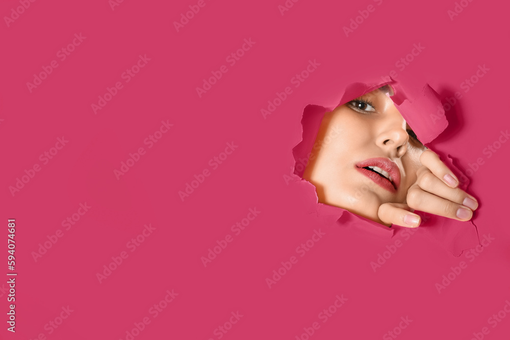 Young woman visible through hole in pink paper