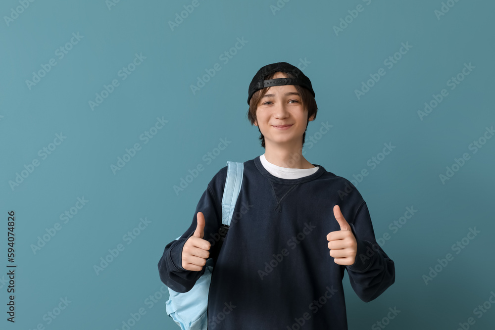 Male student with backpack showing thumbs-up on blue background