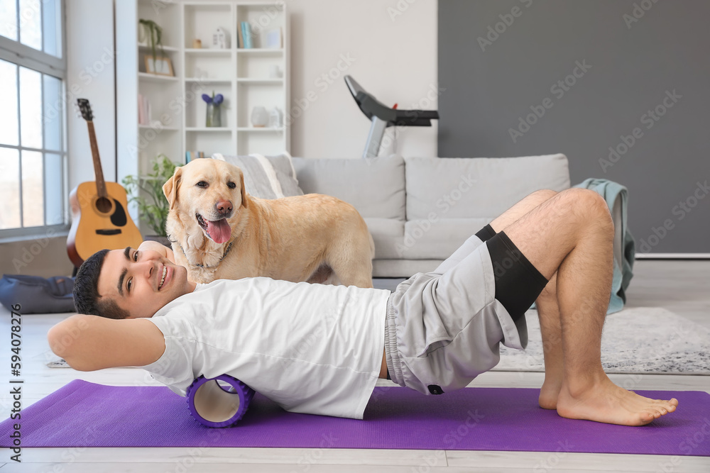 Young man with cute Labrador dog training at home