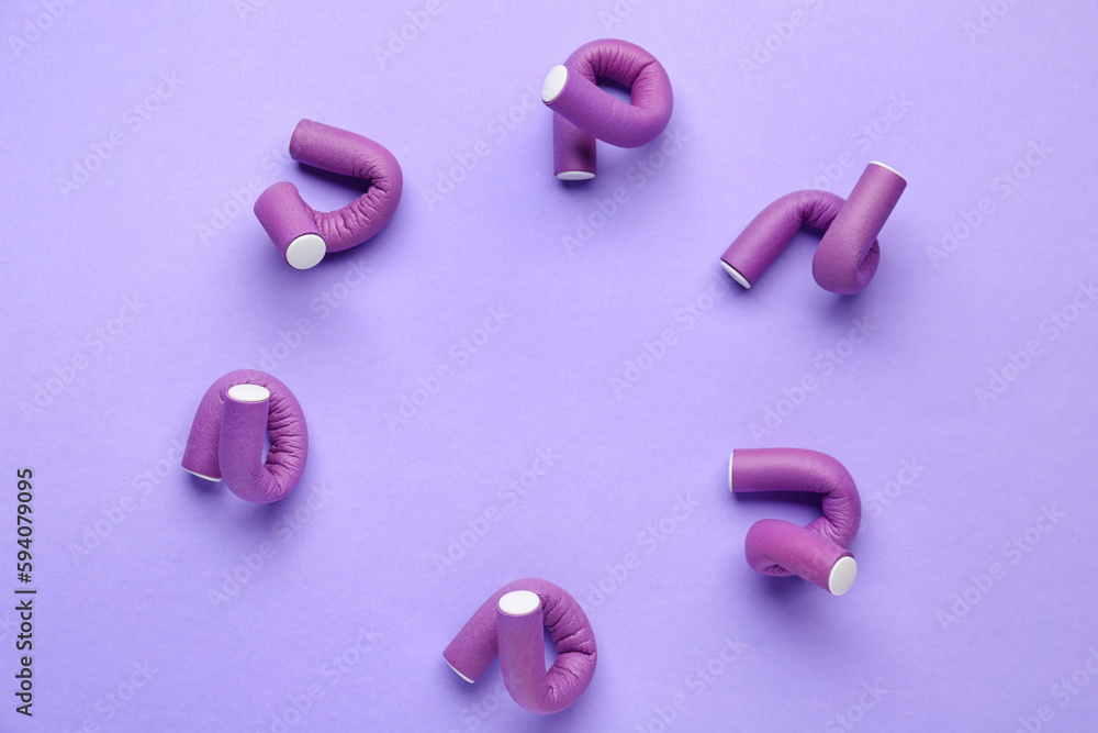 Frame made of hair curlers on lilac background