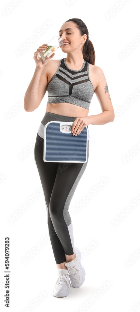 Sporty young woman with scales drinking water on white background