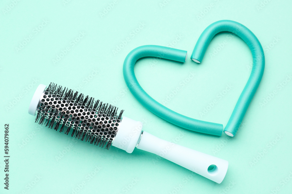 Heart made of curlers with brush on mint background