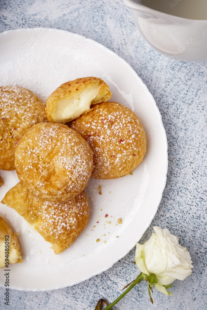 Plate with tasty choux dessert on light background, closeup