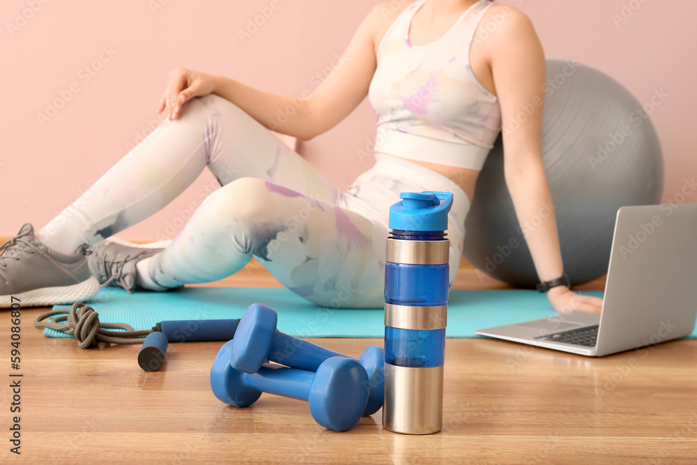 Dumbbells with sports water bottle in gym, closeup