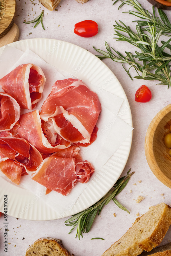 Plate with tasty jamon slices on light background