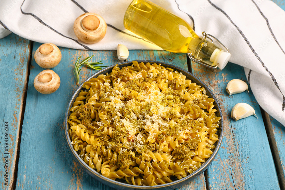 Plate of tasty Italian pasta with Parmesan cheese on blue wooden background