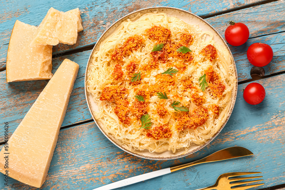 Plate of tasty Italian pasta with Parmesan cheese on blue wooden background