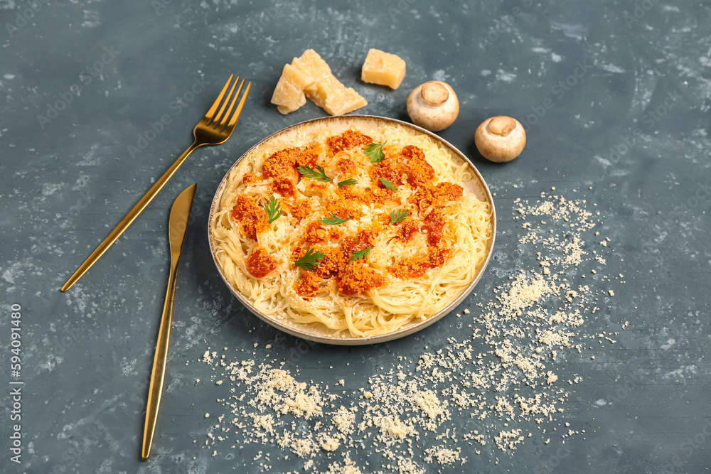 Plate of tasty Italian pasta with Parmesan cheese on blue background