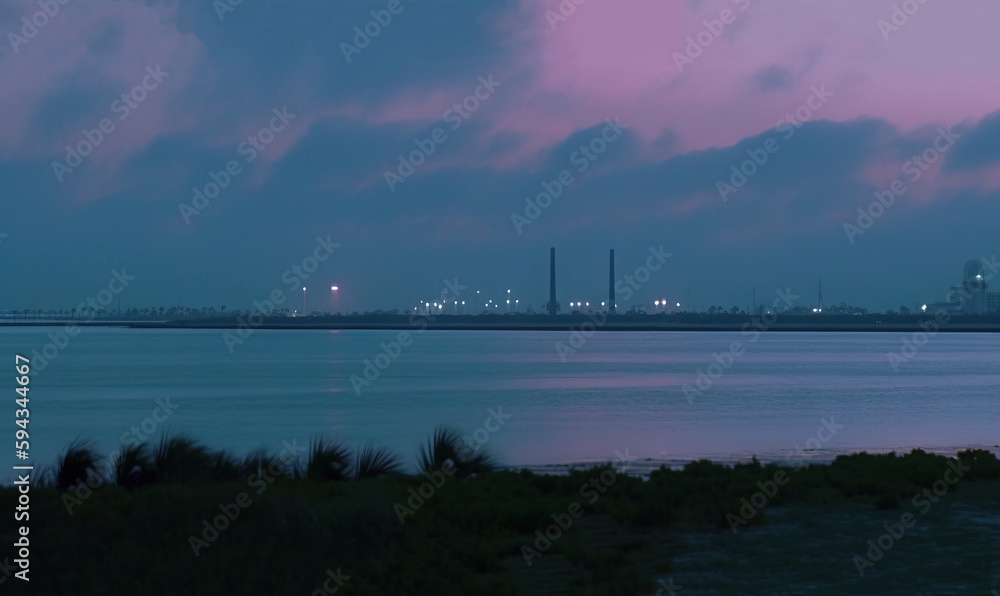  a large body of water with a city in the background at night with clouds in the sky and a few build