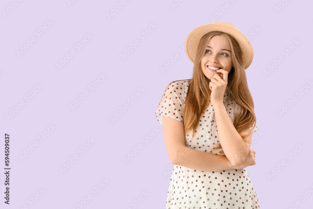 Young woman in hat biting nails on lilac background