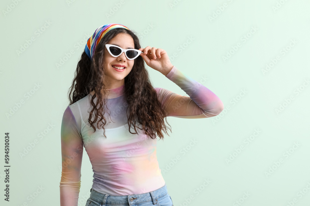 Teenage girl in stylish sunglasses on green background