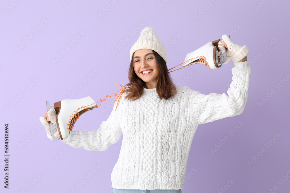 Pretty young woman with ice skates on lilac background