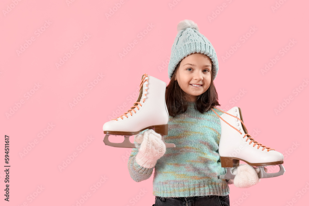 Little girl in winter clothes with ice skates on pink background