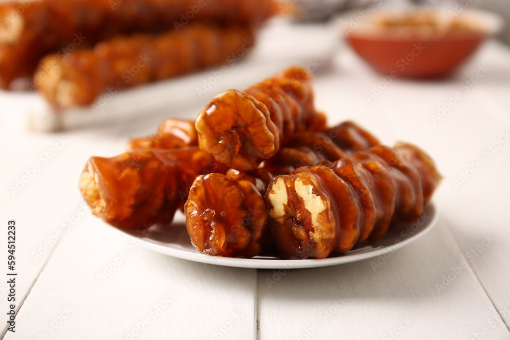 Plate with tasty churchkhela on light wooden background