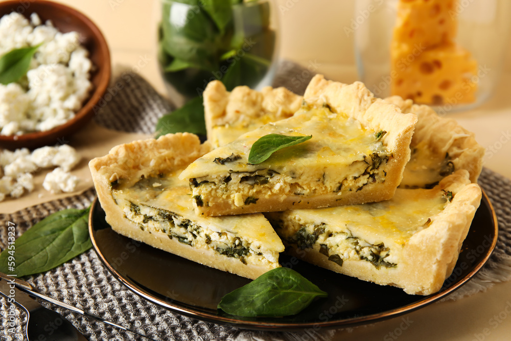 Plate with pieces of delicious quiche on beige background