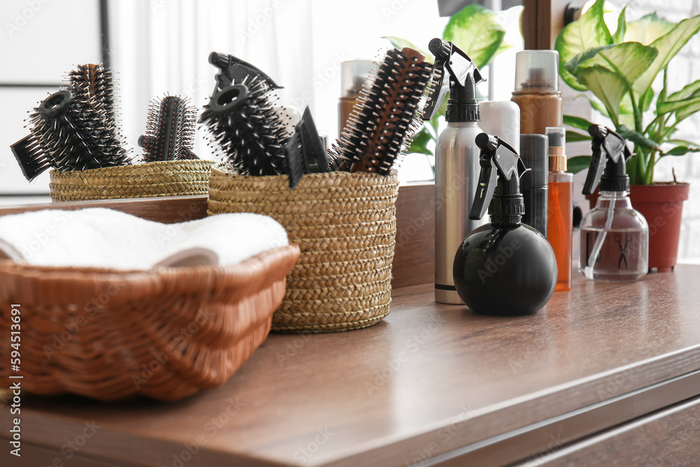 Different hair sprays and brushes on table in beauty salon