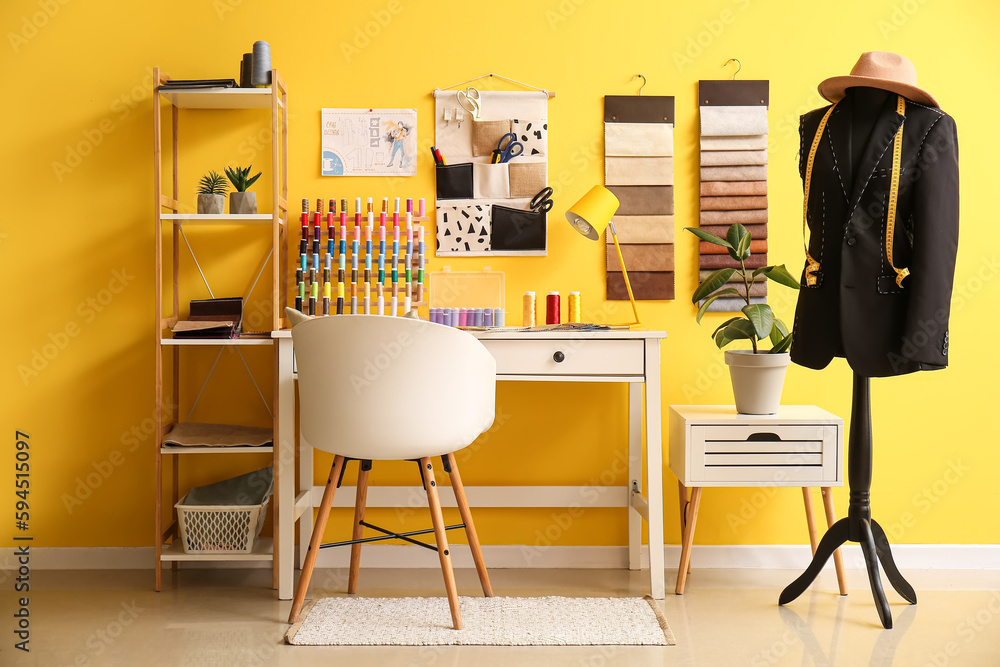 Interior of stylish atelier with tailors workplace, fabric samples and mannequin