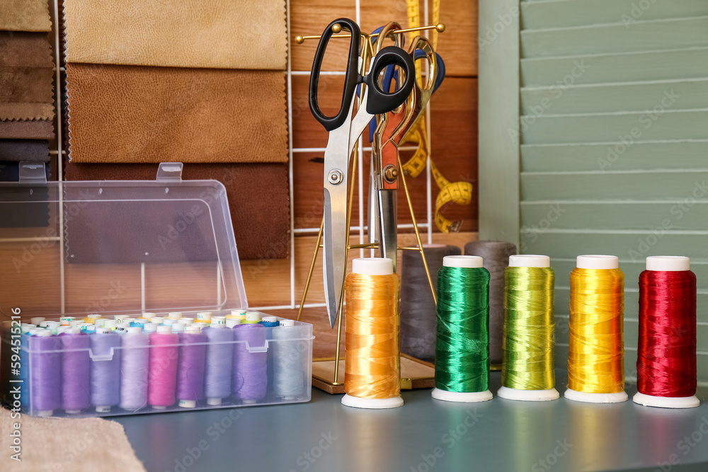 Thread spools with scissors on table in atelier, closeup