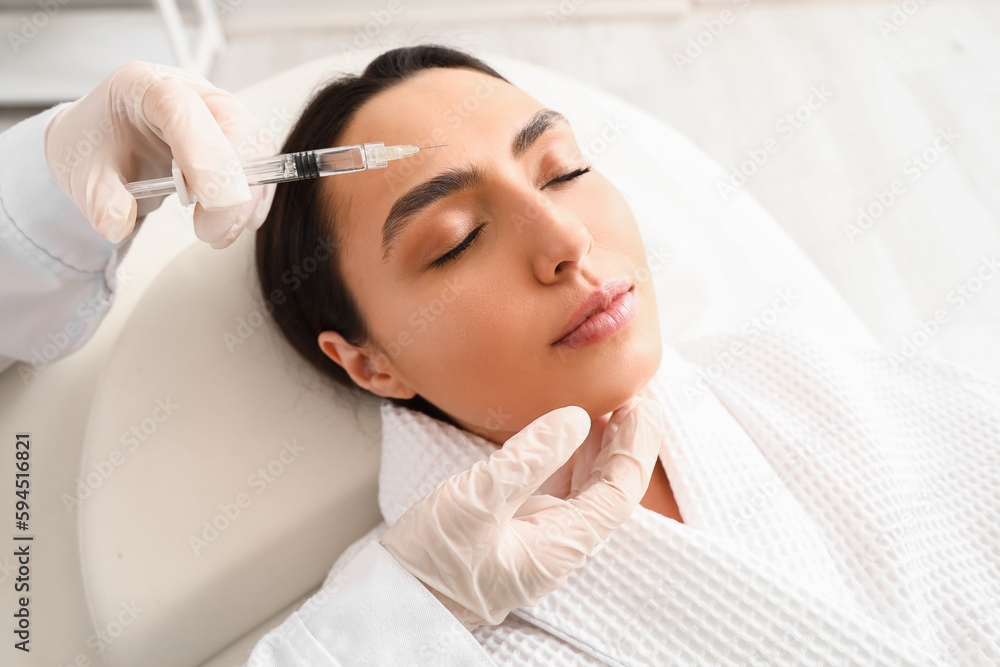 Young woman receiving filler injection in beauty  salon