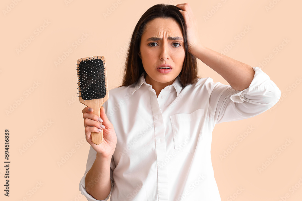 worried young woman with hair loss problem on beige background