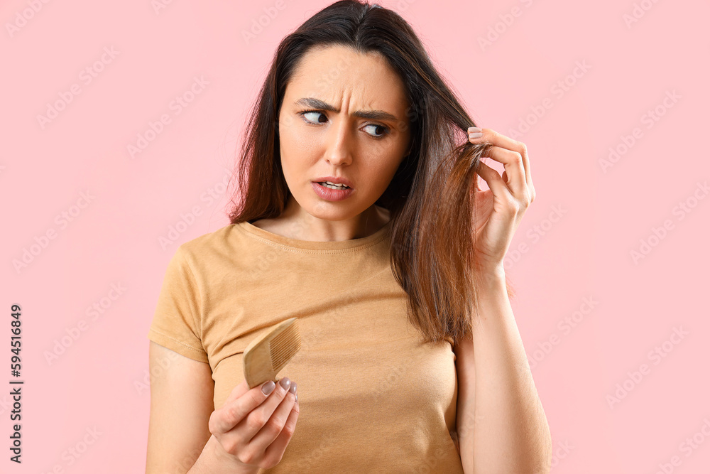 Worried young woman with hair loss problem on pink background