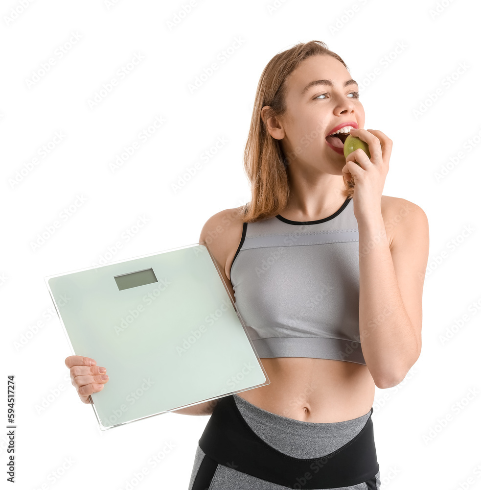 Sporty young woman with scales eating apple on white background