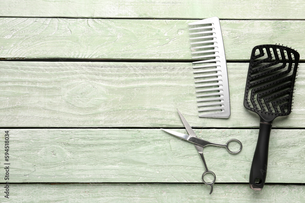 Hair brushes with scissors on green wooden background