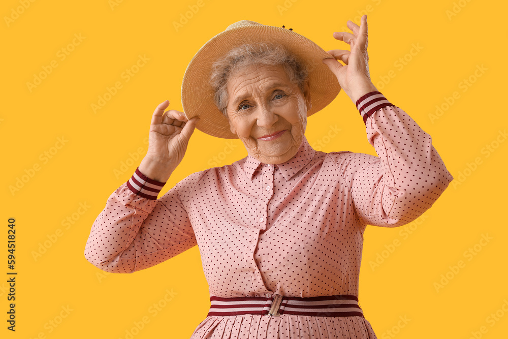 Senior woman in hat on yellow background