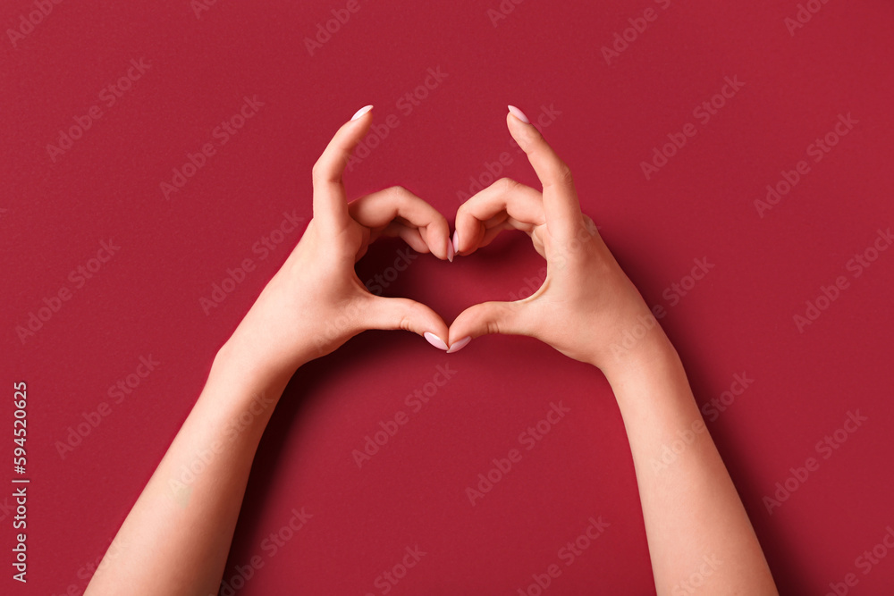 Woman making heart with her hands on red background