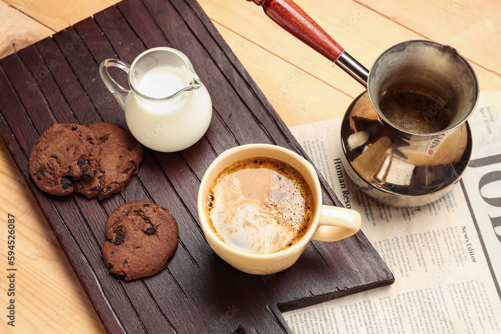 Board with cup of coffee, milk, cookies and cezve on light wooden background, closeup