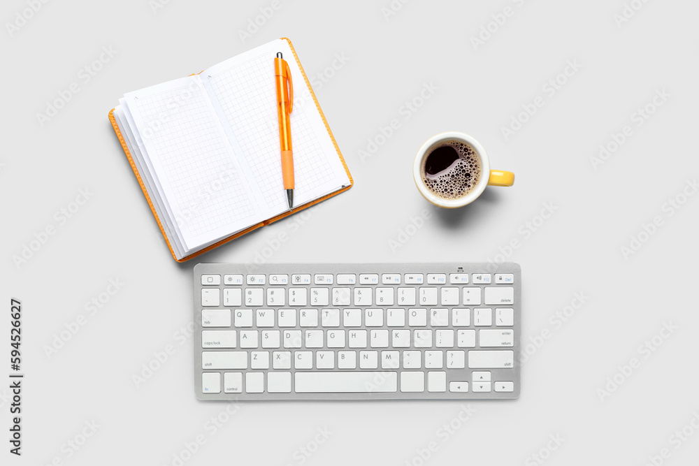 Notebook with pen, cup of coffee and computer keyboard on white background