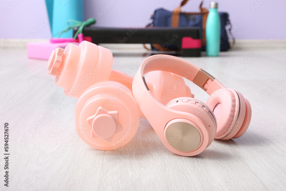 Dumbbells with headphones in gym, closeup