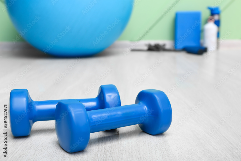 Blue dumbbells on floor in gym, closeup