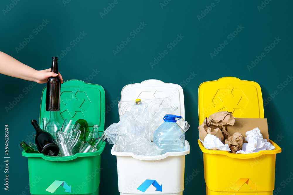 Woman throwing garbage into trash bin near green wall. Recycling concept