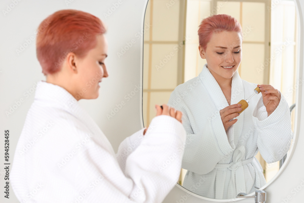 Young woman with serum in bathroom