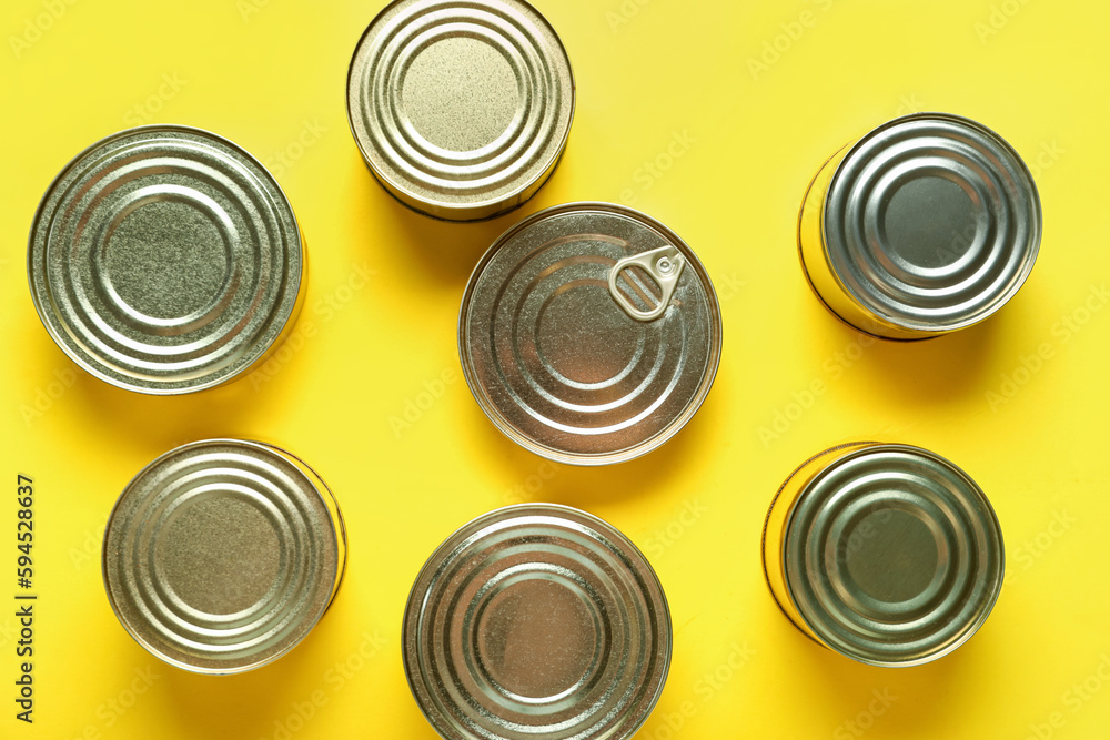 Assortment of tin cans with fish on yellow background