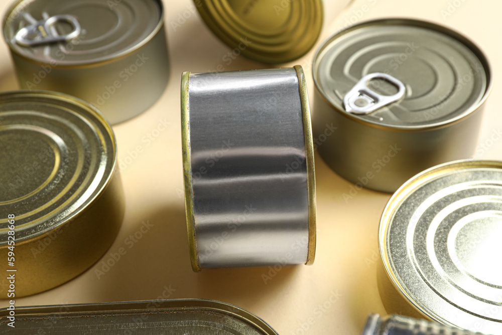 Tin cans with fish on beige background, closeup