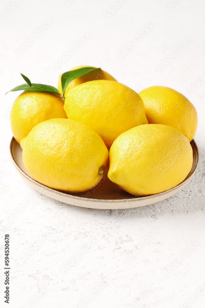 Plate with fresh lemons on white background