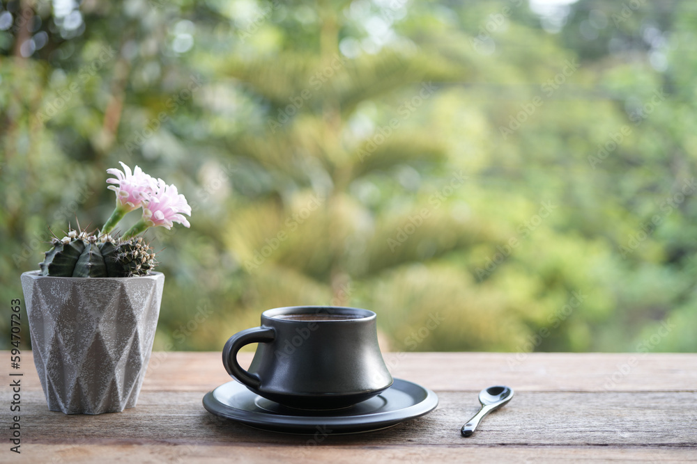 Earthenware tea cup and pink cactus flower on wooden table