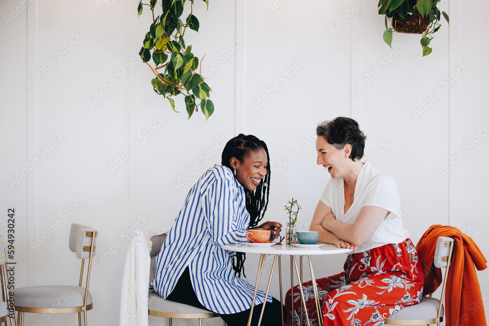 Happy friends laughing together in coffee shop