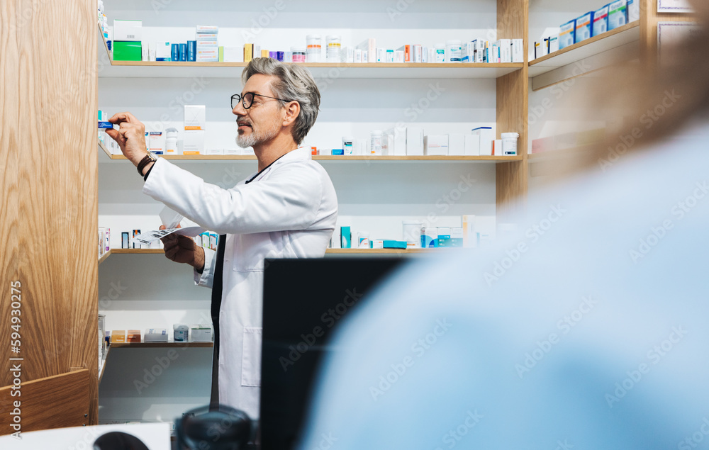 Male pharmacist assisting a patient with a prescription in a chemist