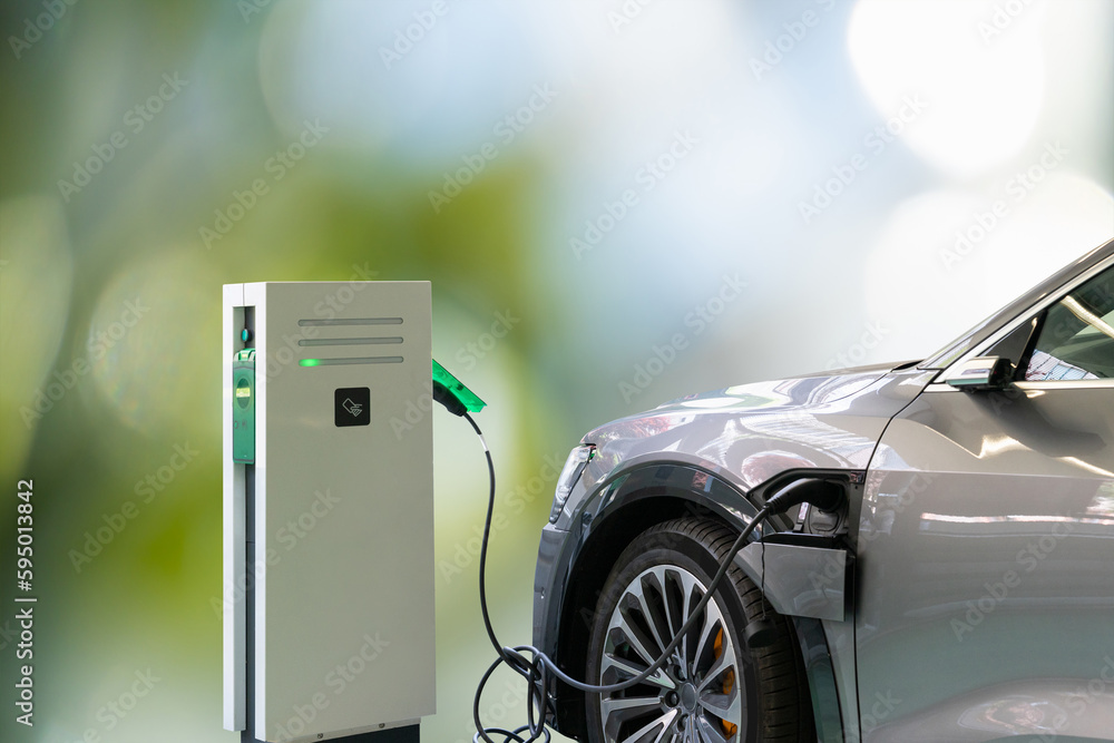 Electric car with a connected charging cable on a green background	