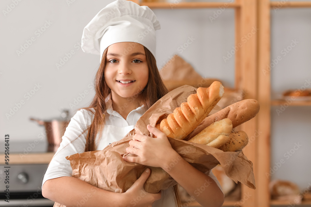 Little baker with tasty baguettes in kitchen