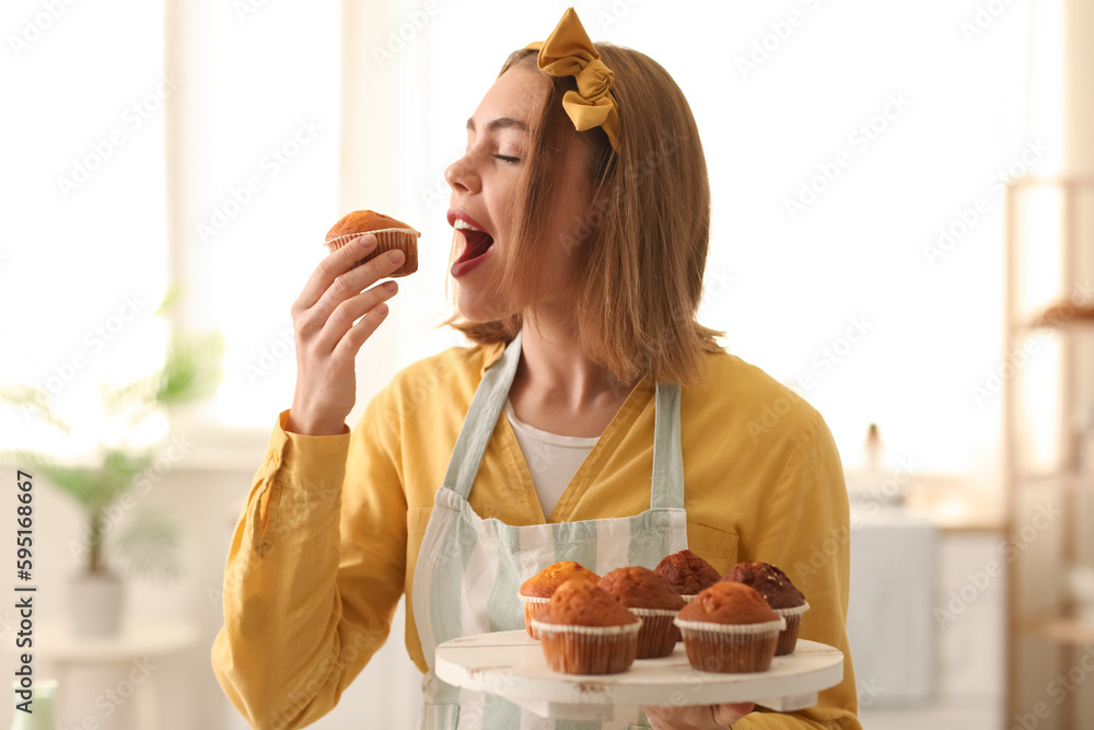 Female baker eating tasty cupcake in kitchen