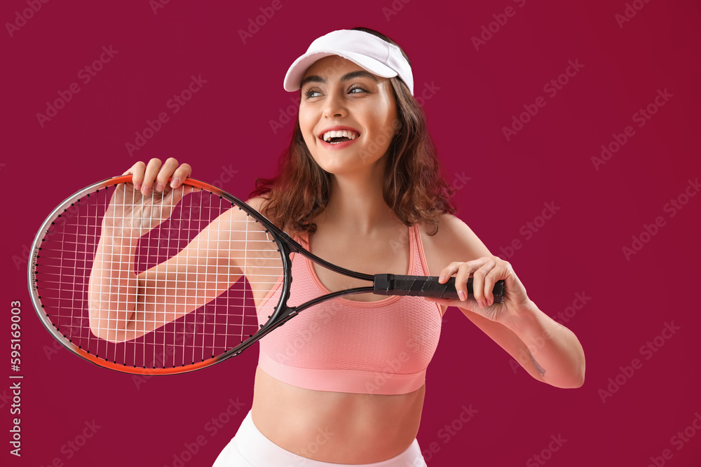 Young woman with tennis racket on pink background